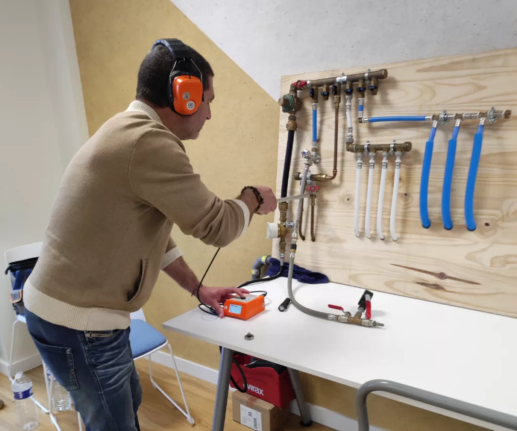 Formation ADRÉ Eau de notre Campus : un technicien prit en photo utilisant un détecteur électroacoustique pour localiser une fuite sur un banc pédagogique au Campus ADRÉ.
